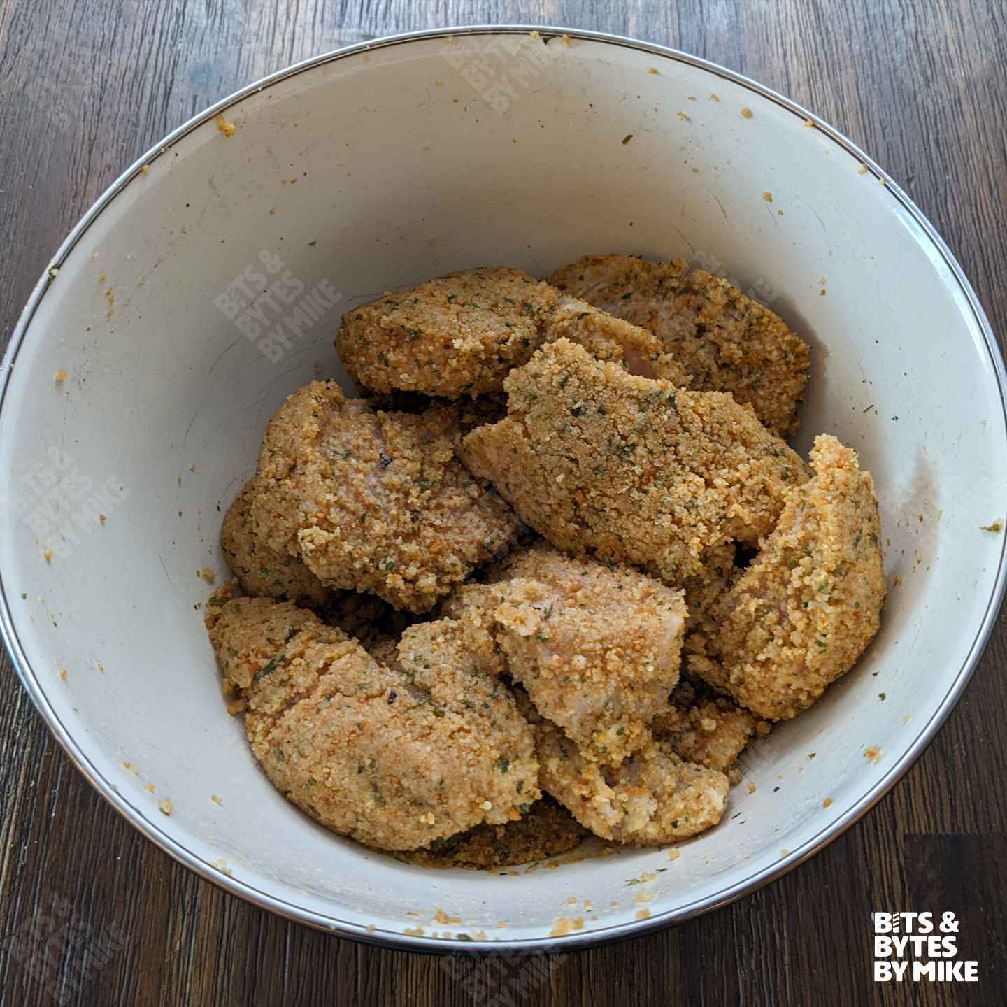 Chicken tenders in bowl after being coated in bread crumbs and before being baked.